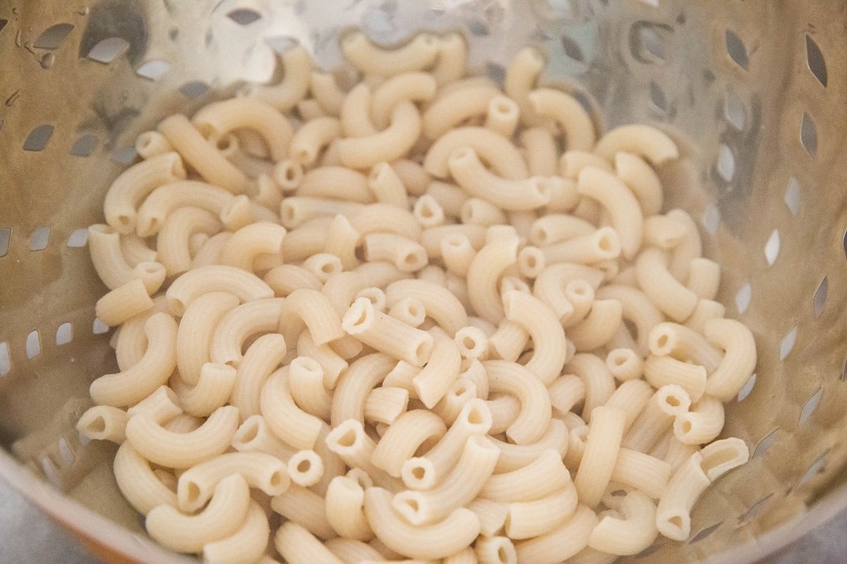 Elbow noodles (also known as macaroni noodles) in a colander being drained after cooking.