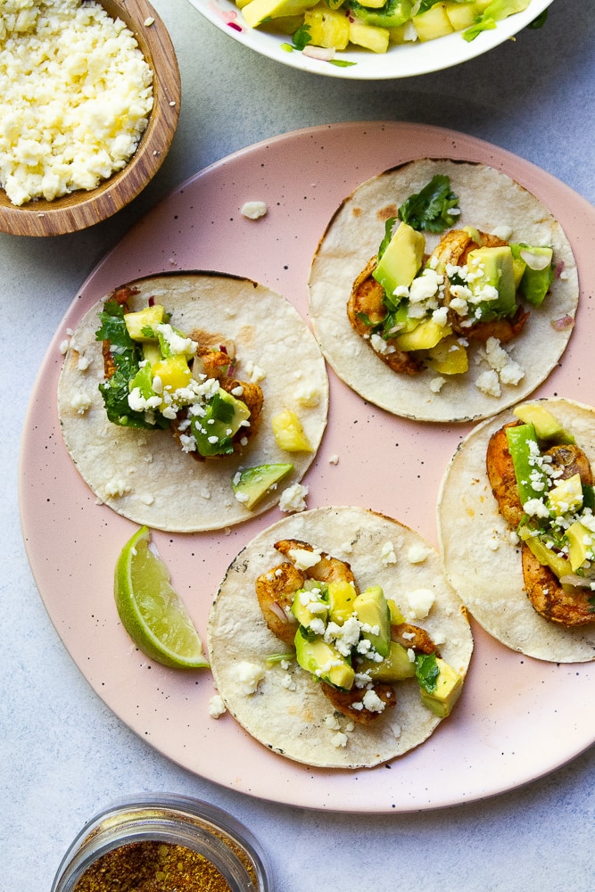 Grilled Shrimp Tacos on a plate with salsa and cheese sprinkled on top