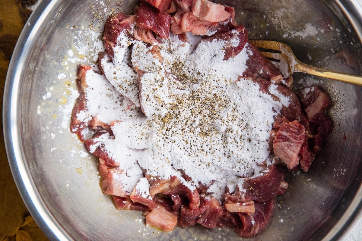 Mixing bowl with egg, sliced steak and tapioca flour, ready to be breaded and pan-fried.