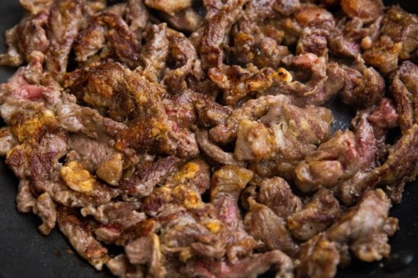 Breaded steak strips browning in a skillet.