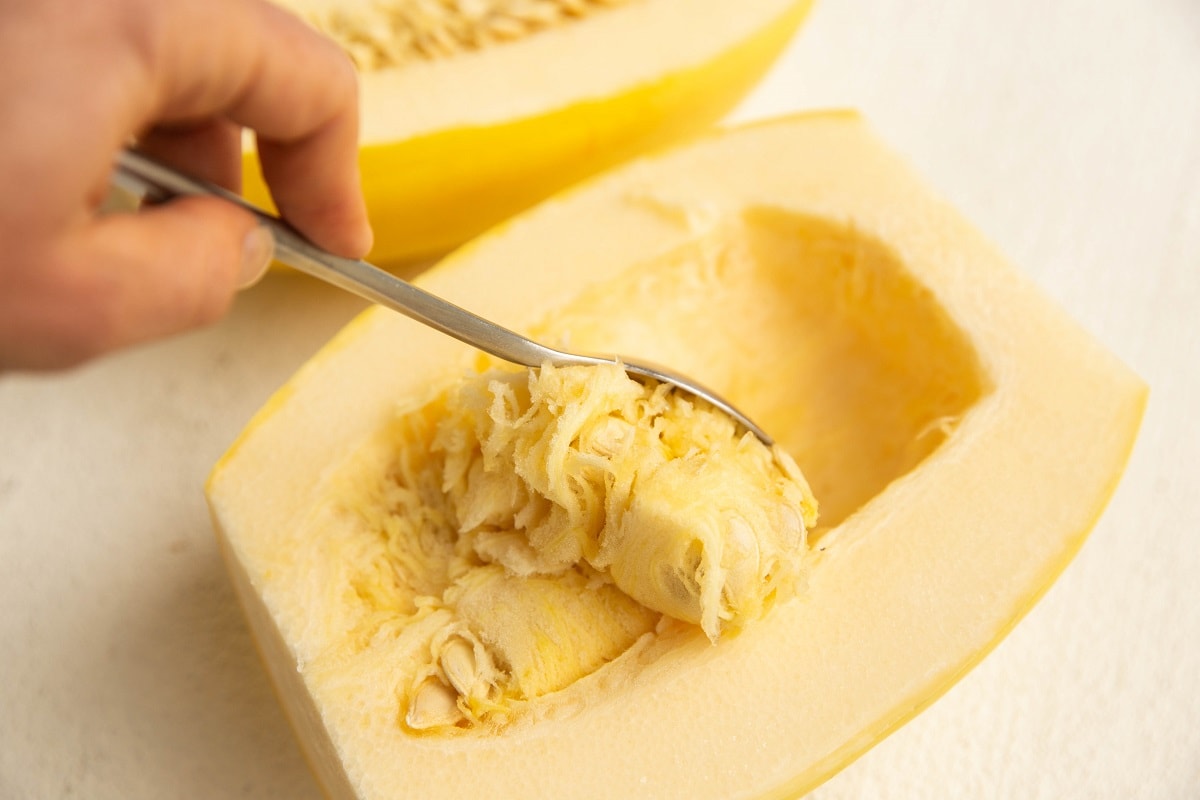 Spoon scooping out the insides and seeds of the spaghetti squash.