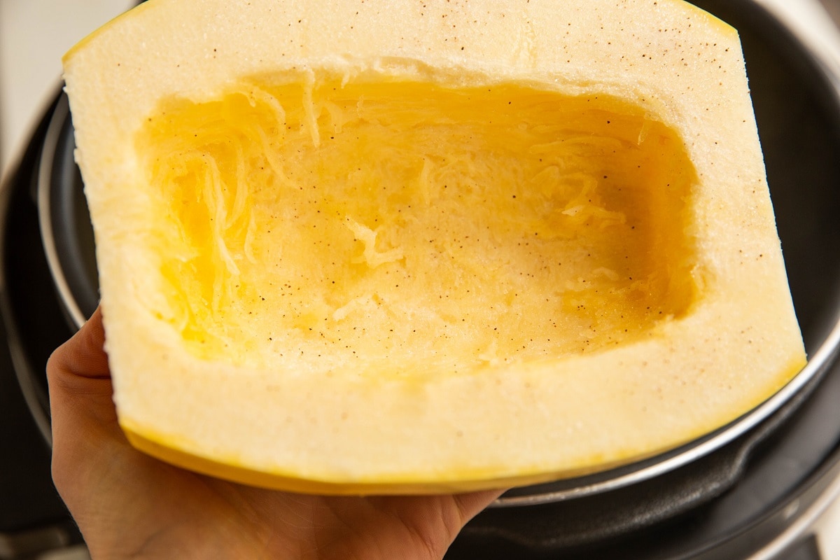 Hand holding a spaghetti squash half sprinkled in salt.