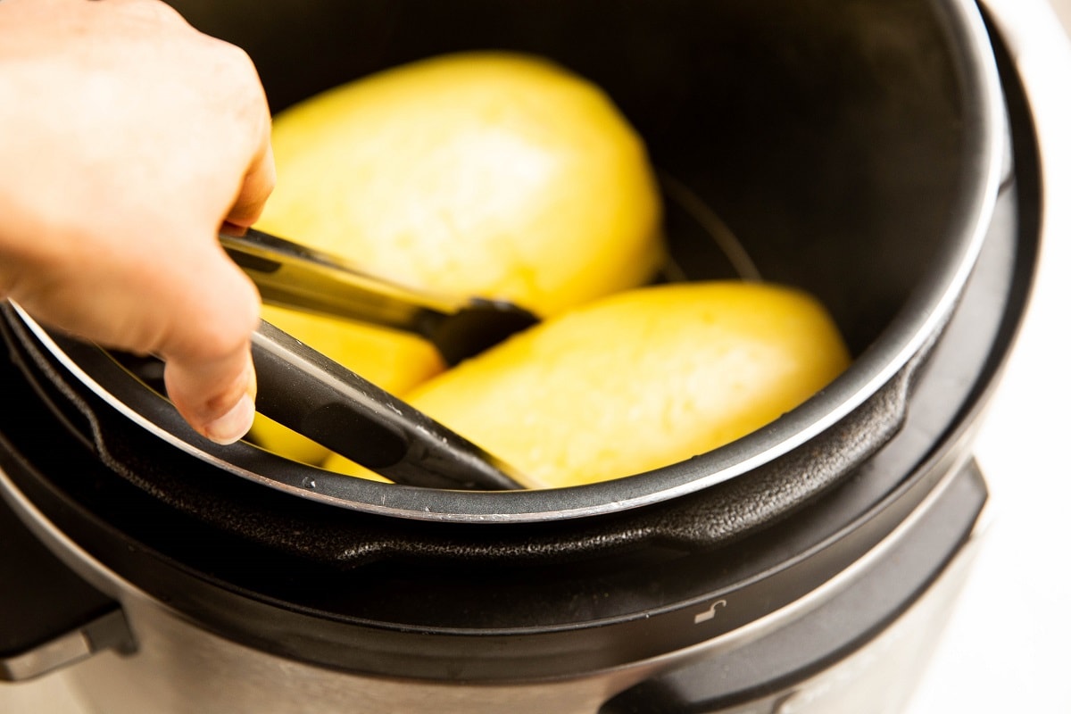 Using tongs to bring the spaghetti squash out of the instant pot.