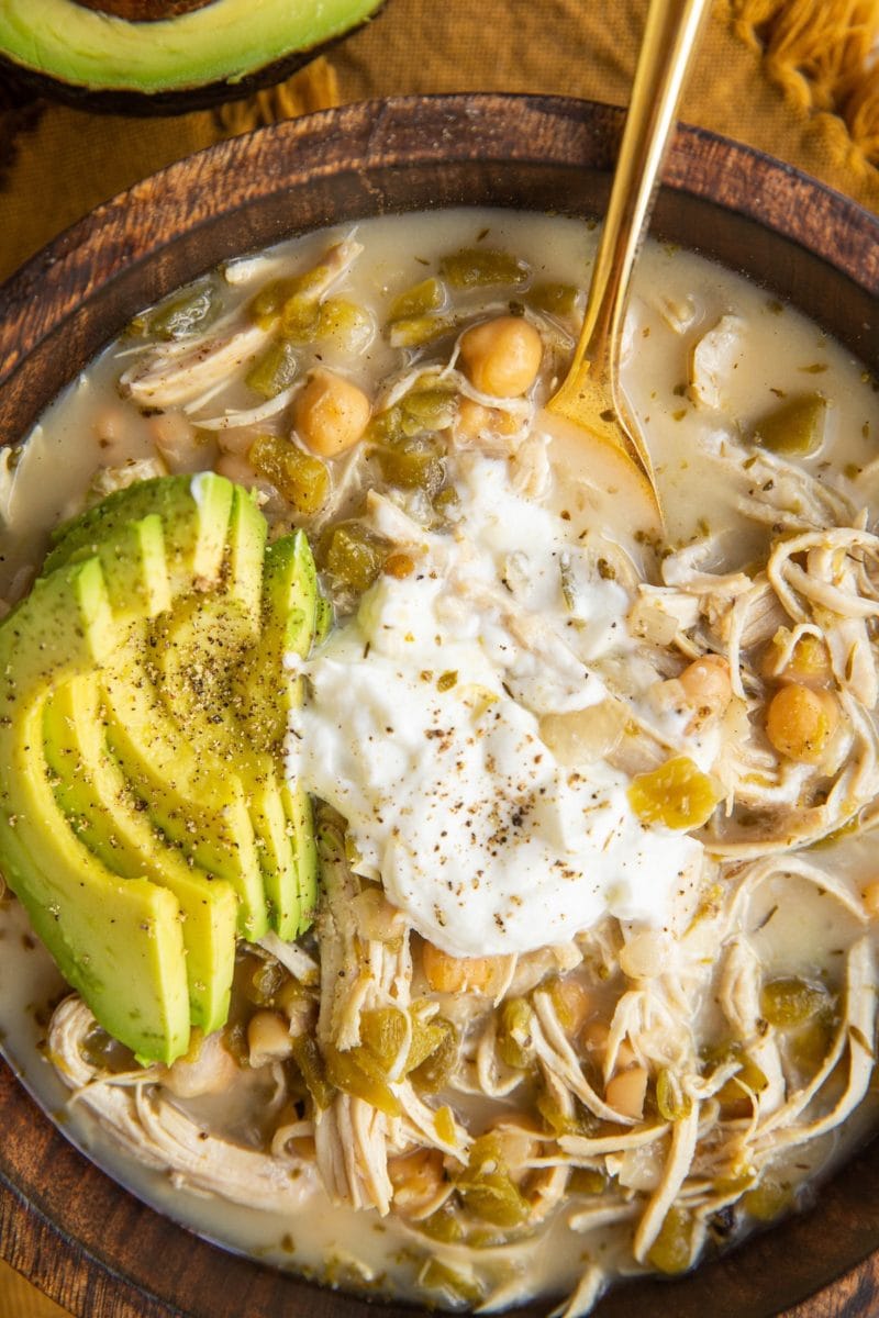 Top down big wooden bowl of chili with a golden spoon inside about to take a scoop.