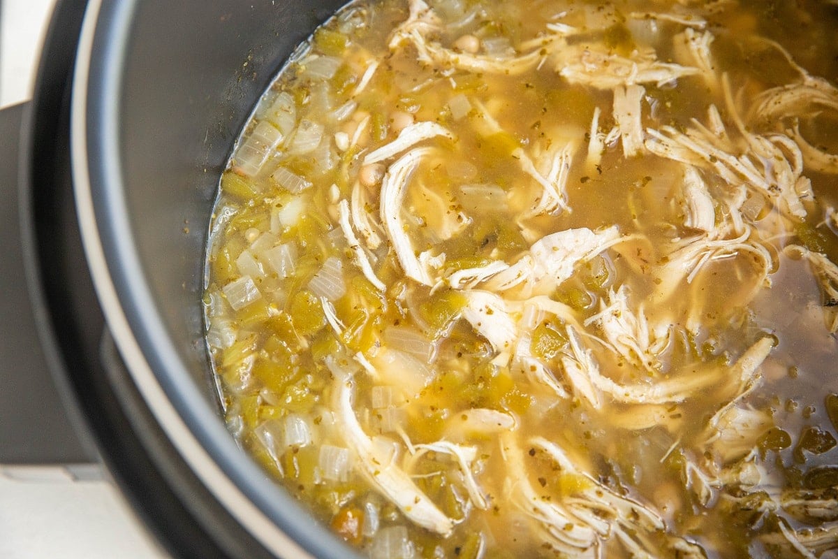White Chicken Chili inside a pressure cooker with shredded chicken and white beans