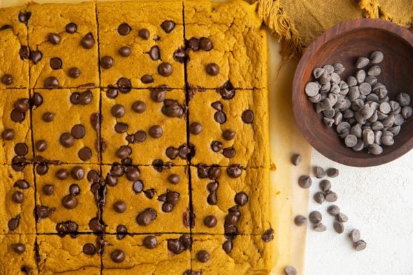 horiztonal photo of sliced pumpkin baked oats on a sheet of parchment paper with chocolate chips all around.