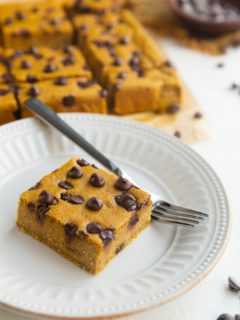 Pumpkin Blended Baked Oats square on a white plate with sliced of baked oats in the background.