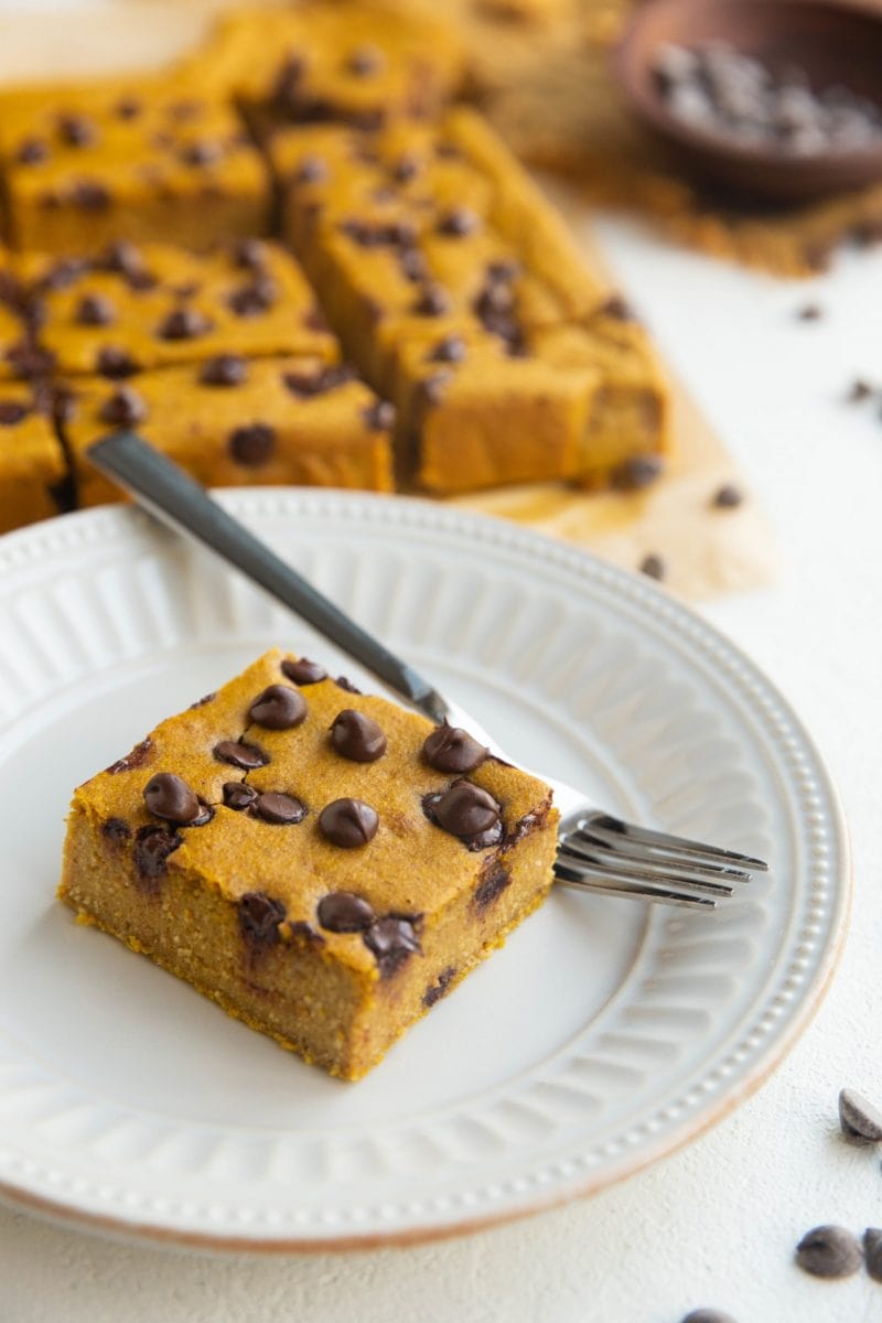 Pumpkin Blended Baked Oats square on a white plate with sliced of baked oats in the background.