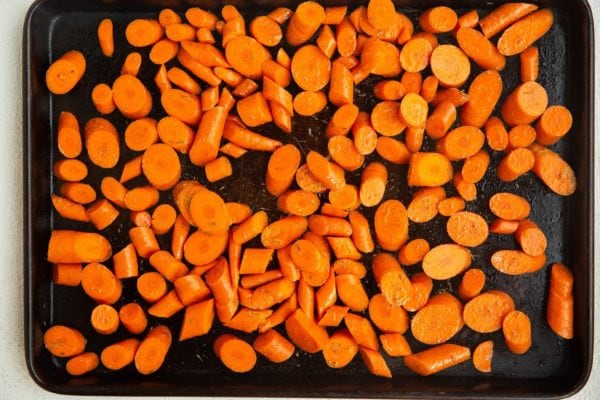 baking sheet with carrots spread over it, waiting to go into the oven.