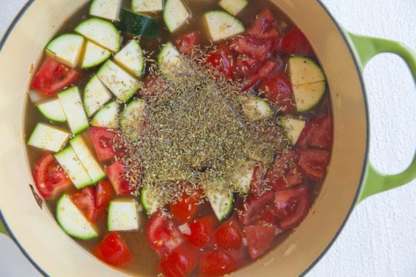 Soup pot with veggies and herbs.