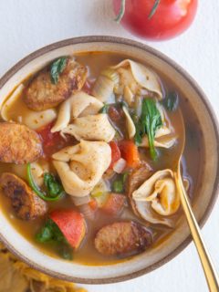 Big bowl of soup with a tomato and napkin to the side.