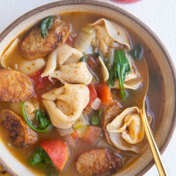 Big bowl of soup with a tomato and napkin to the side.