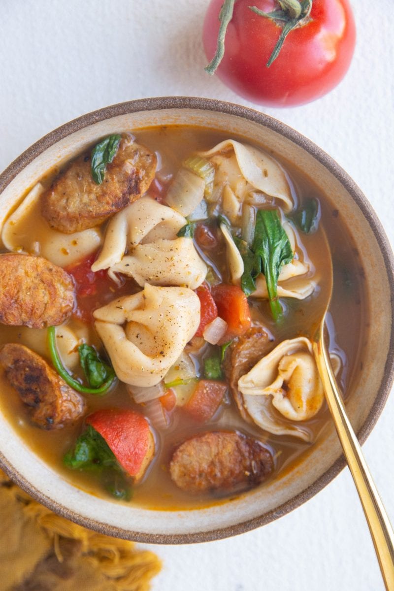 Big bowl of soup with a tomato and napkin to the side.