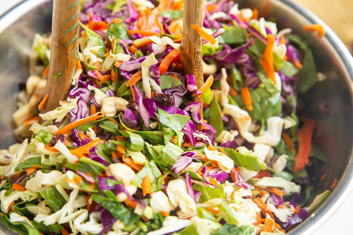 Scooping salad out of the bowl with salad tongs.