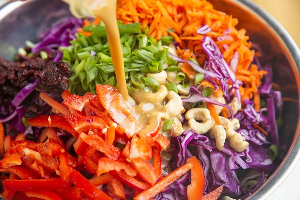 Pouring peanut dressing over the salad