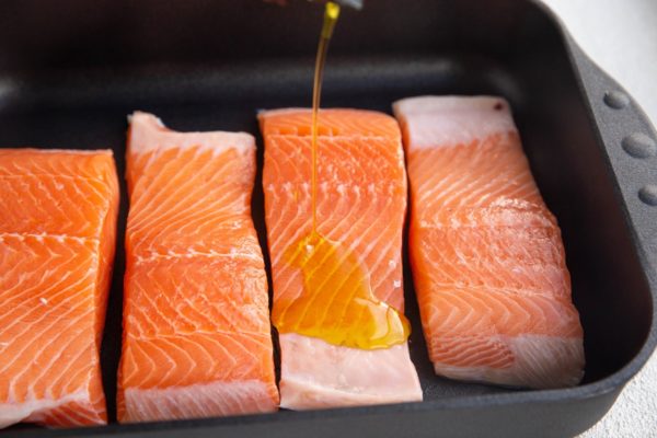 Oil being drizzled over the raw salmon