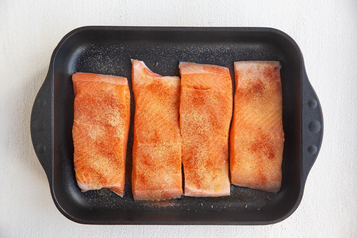 Salmon sprinkled with seasonings in a casserole dish.