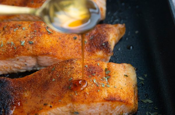 Cooked salmon with glaze being poured over it.