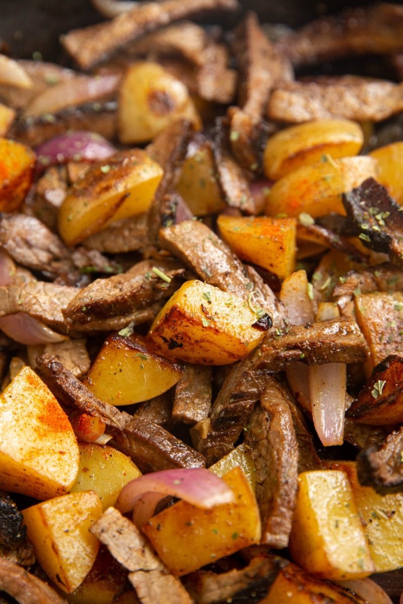 Close up image of crispy potatoes and tender steak strips.