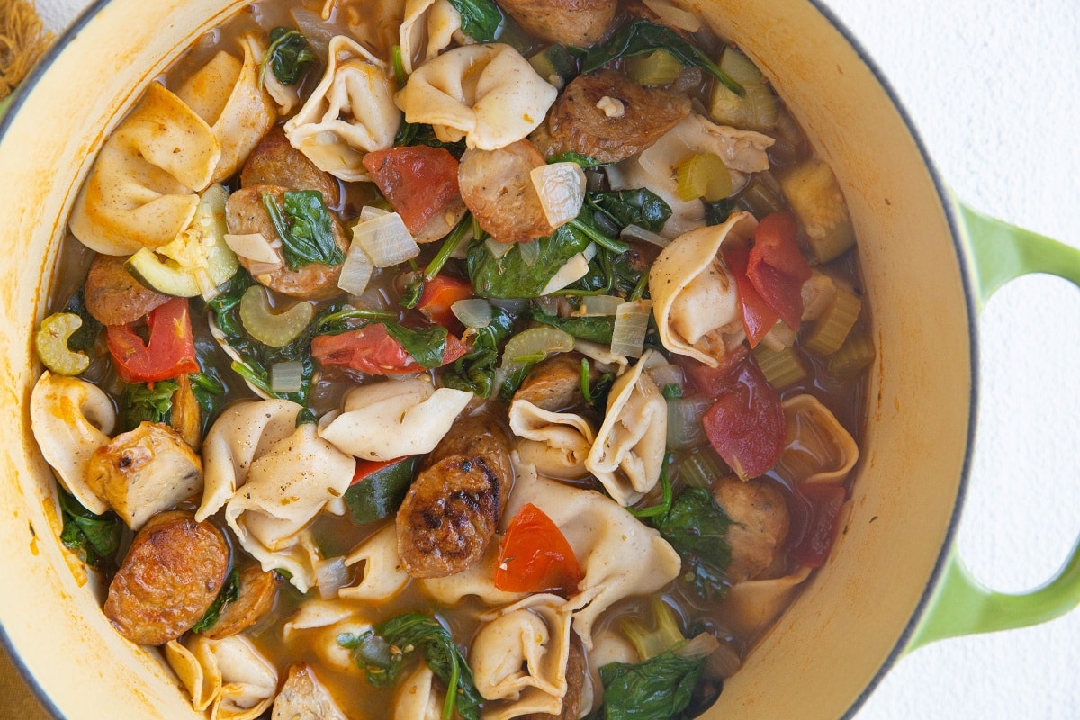 Horizontal image of big pot of tortellini soup.