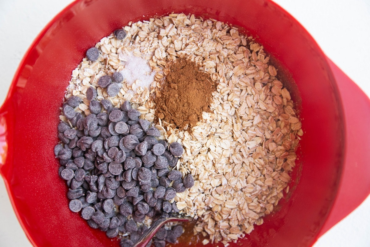 Red mixing bowl with wet mixture on the bottom and dry ingredients on top, ready to be mixed in.