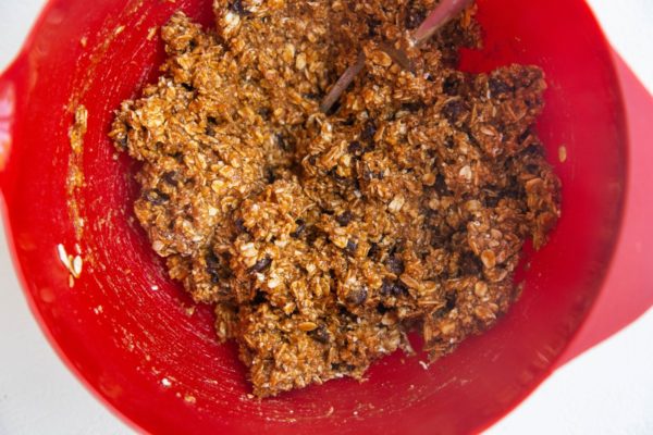 Red mixing bowl with pumpkin oatmeal cookie dough.