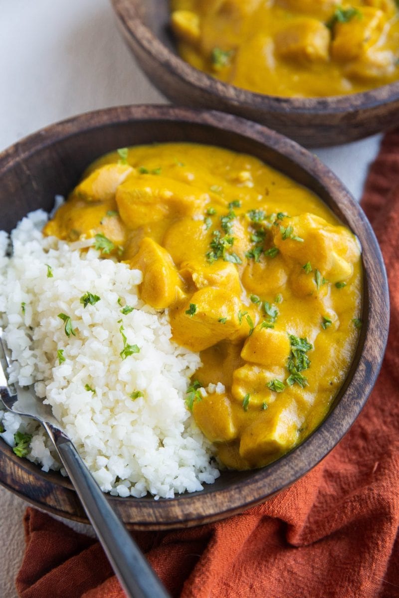 Two wooden bowls full of chicken tikka masala and cauliflower rice.