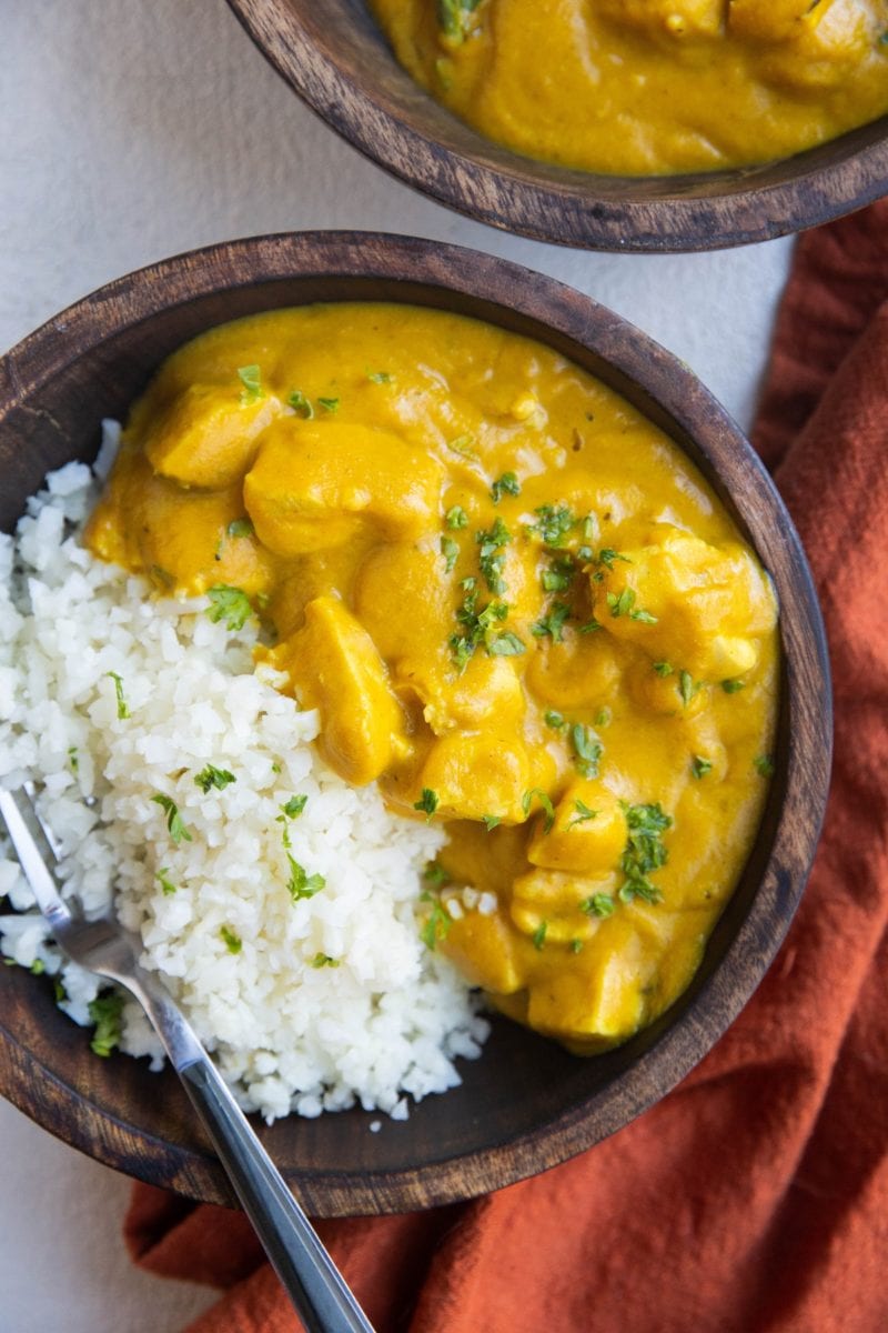 top down image of two wooden bowls of chicken tikka masala served with cauliflower rice