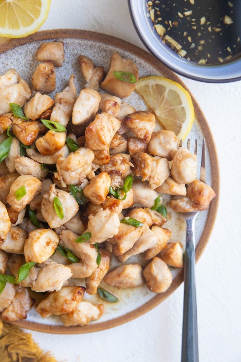 Plate of air fryer chicken bites with a bowl of dipping sauce to the side.