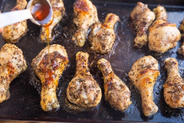 Horizontal photo of chicken drumsticks being drizzled with honey