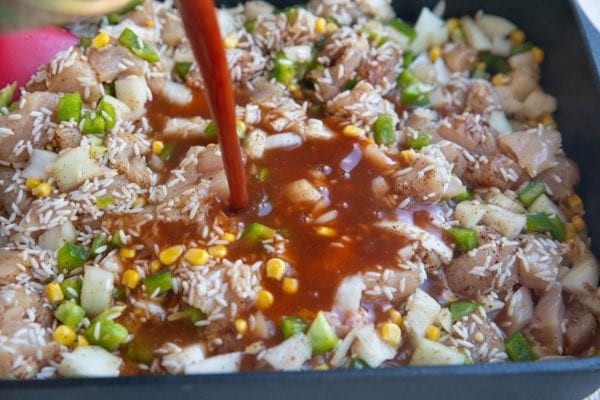 Pouring enchilada sauce and broth into the casserole dish