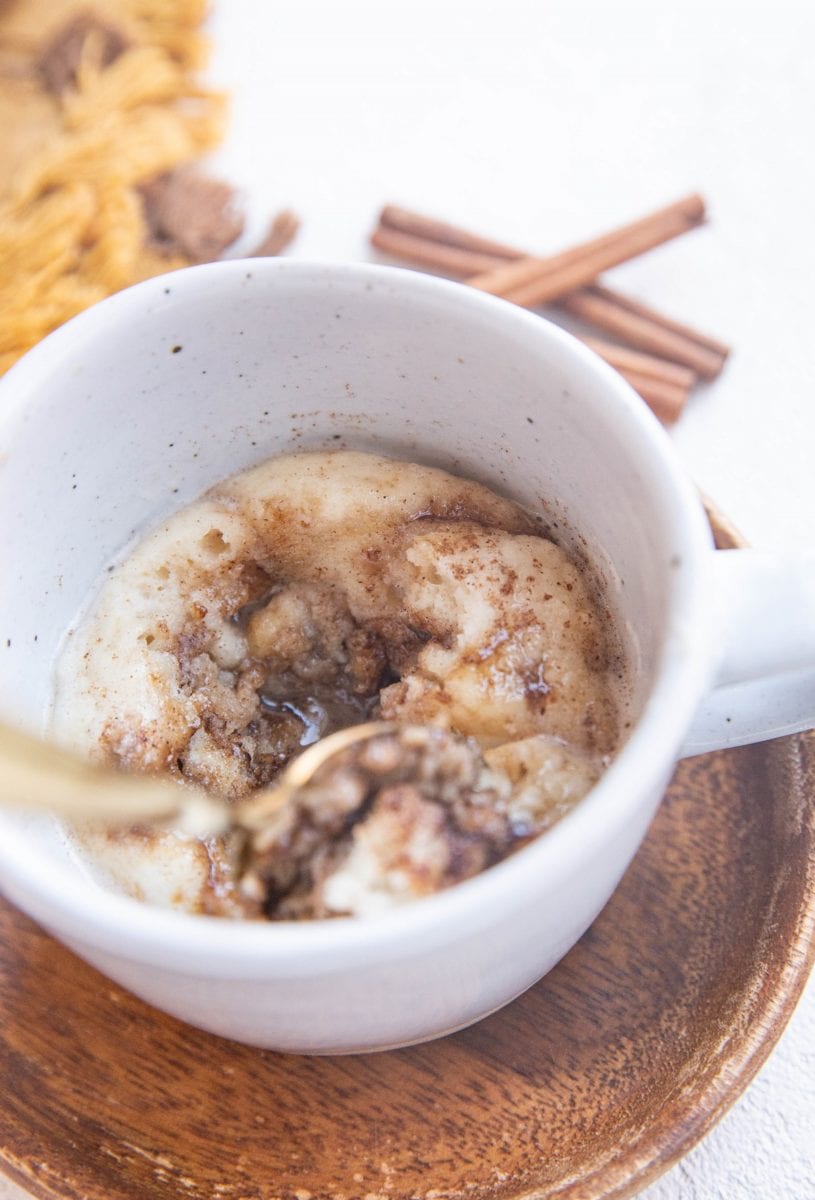 Spoon scooping some cinnamon roll to the side so you can see the center.