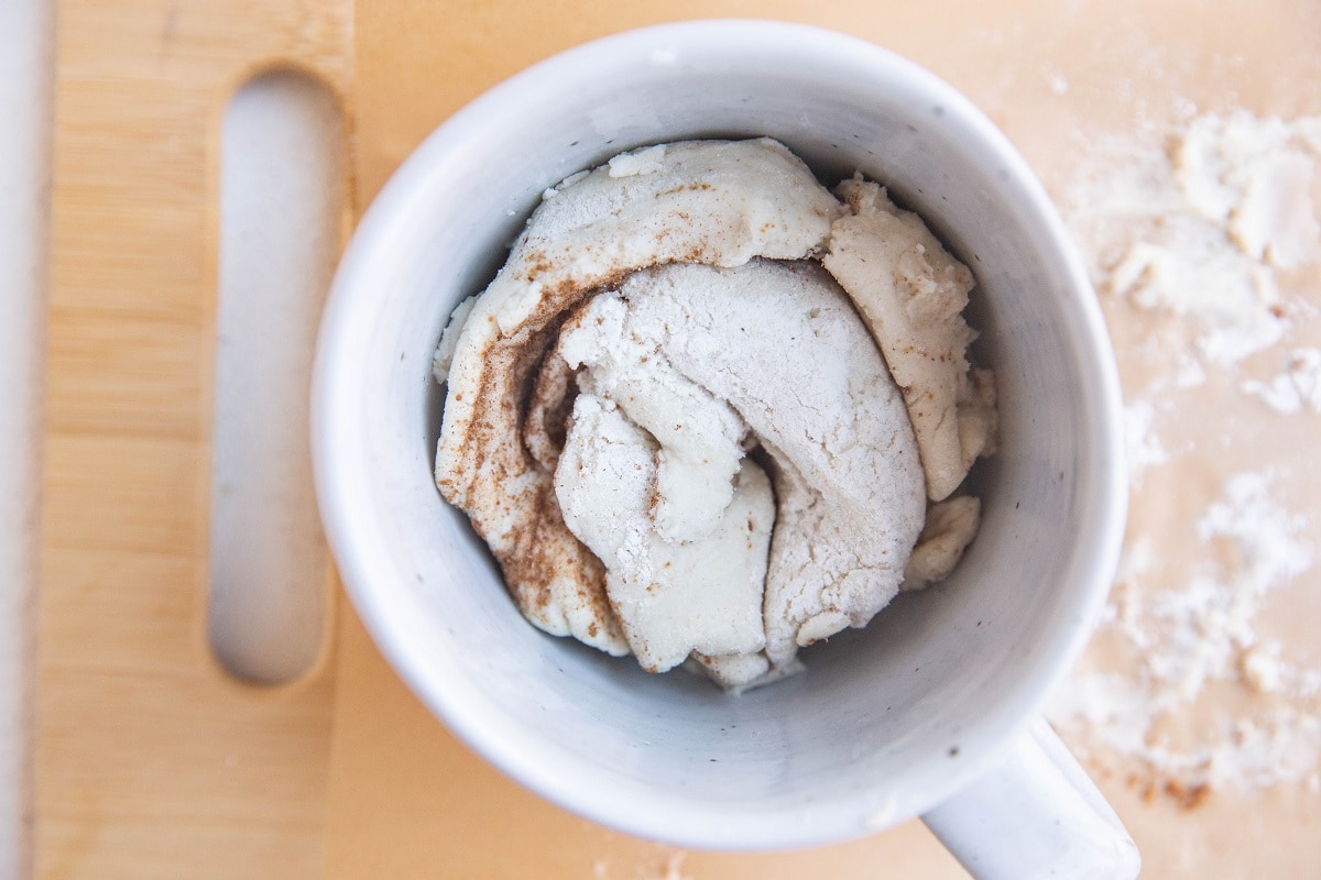 Cinnamon roll for one in a mug, ready to be microwaved.