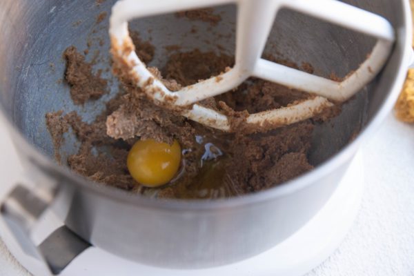 Stand mixer with butter and sugar mixed together and eggs being mixed in.