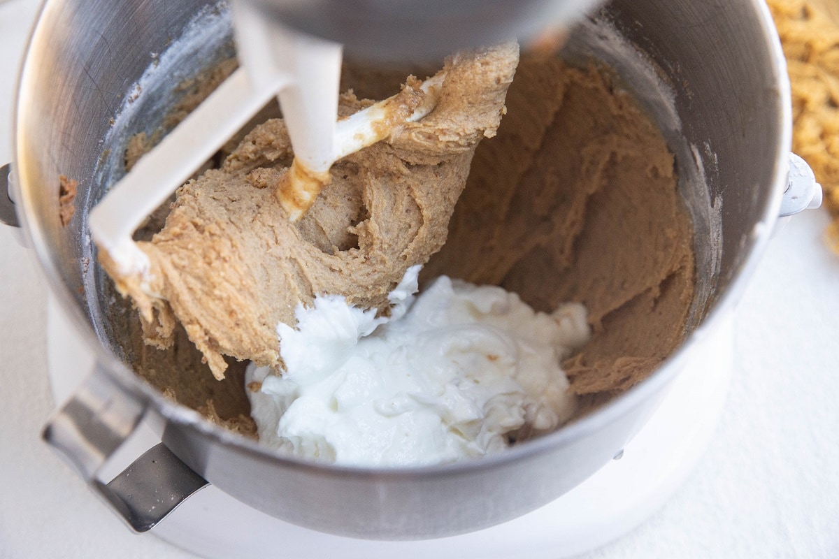 Mixer with apple bread dough and yogurt being mixed in.