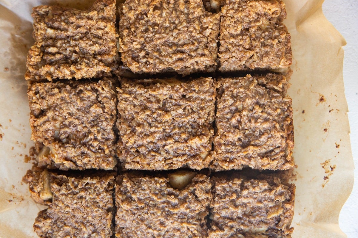 apple bars on a sheet of parchment paper cut into squares.