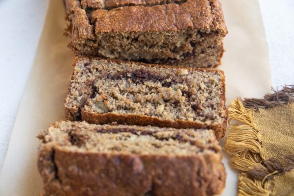 horizontal photo of a sliced loaf of banana bread with cinnamon ribbon in the middle.