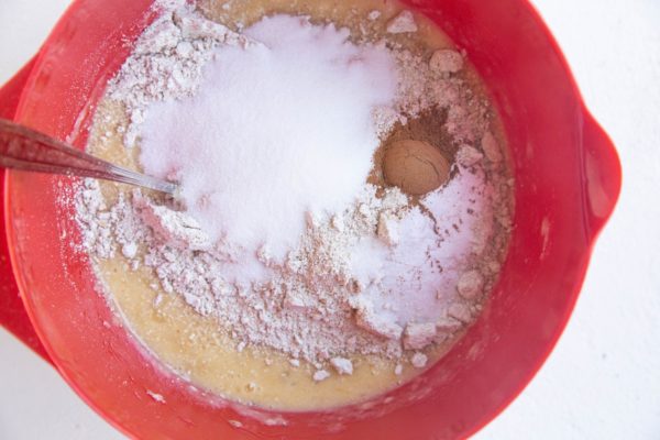 Wet ingredients in a mixing bowl with dry ingredients on top.