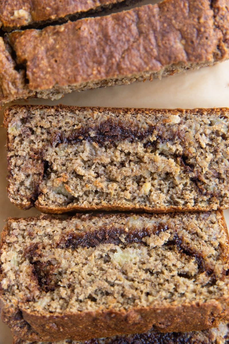 Slices of cinnamon swirl banana bread on a sheet of parchment paper.