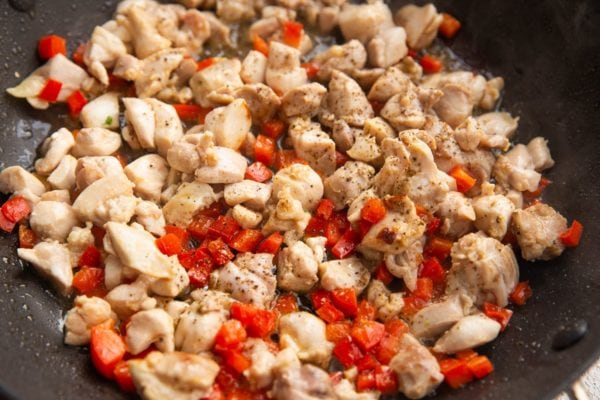 Chicken and bell peppers cooking in a skillet