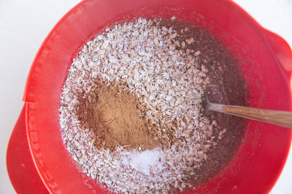 Wet ingredients in a mixing bowl with dry ingredients on top.