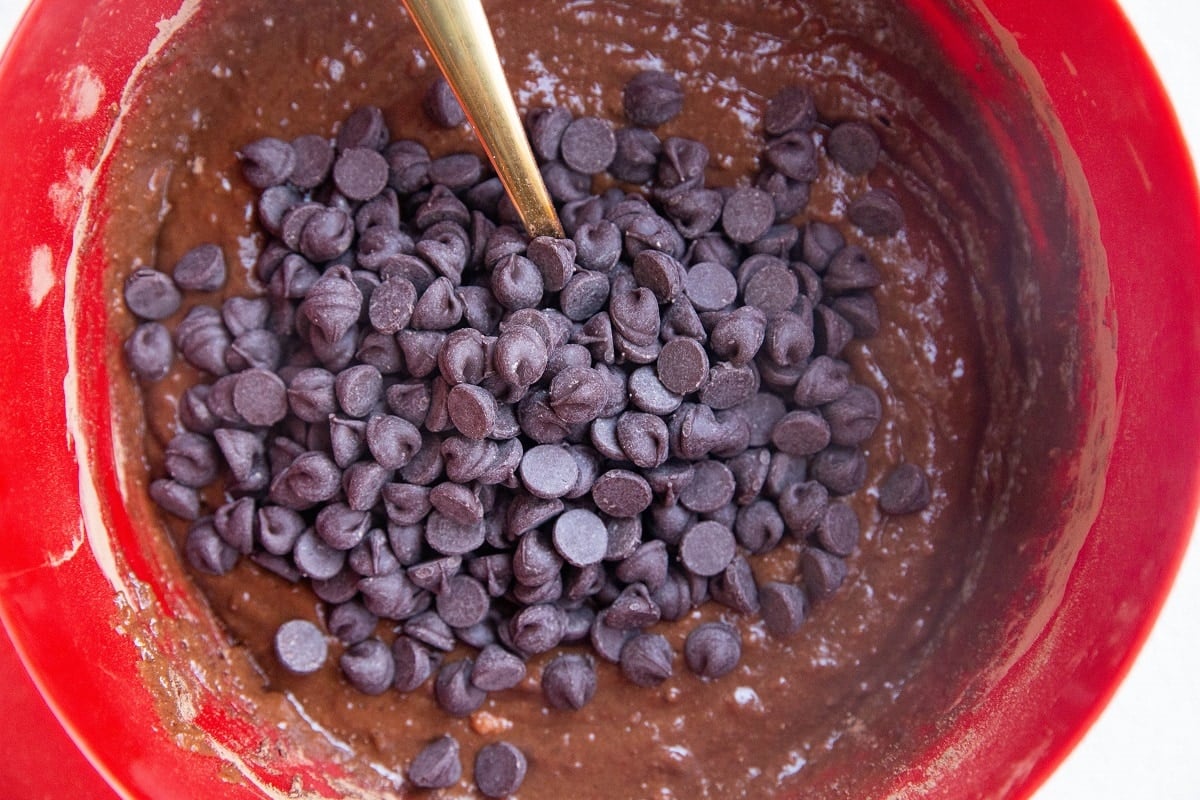 Sweet potato brownie batter in a mixing bowl with chocolate chips on top.