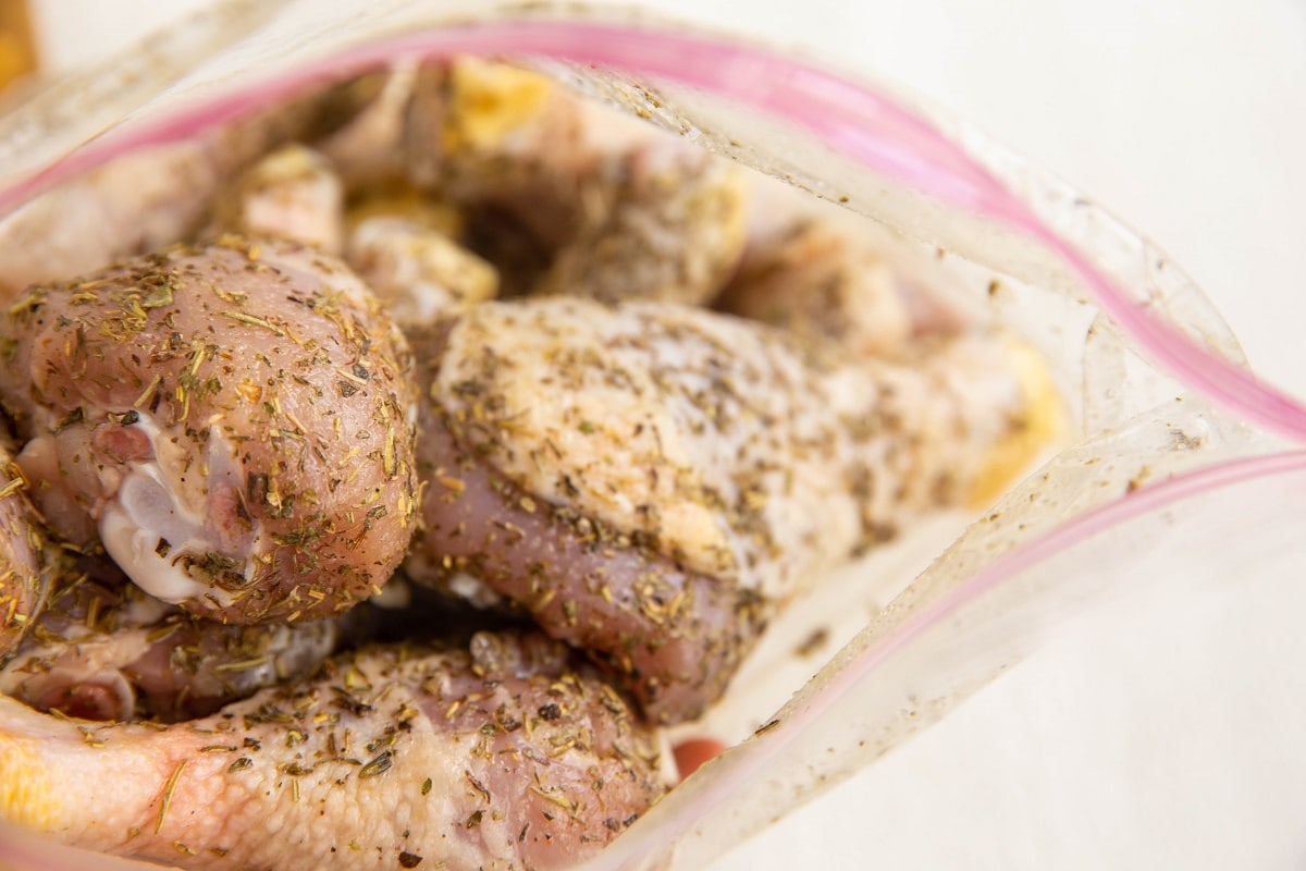 Zip lock bag of chicken legs with seasonings for marinade.
