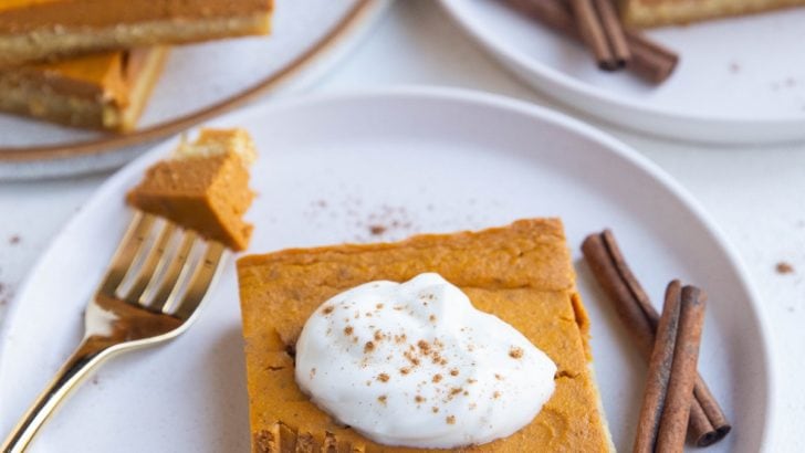 Three plates with slices of keto pumpkin pie on them with one with a bite taken out.
