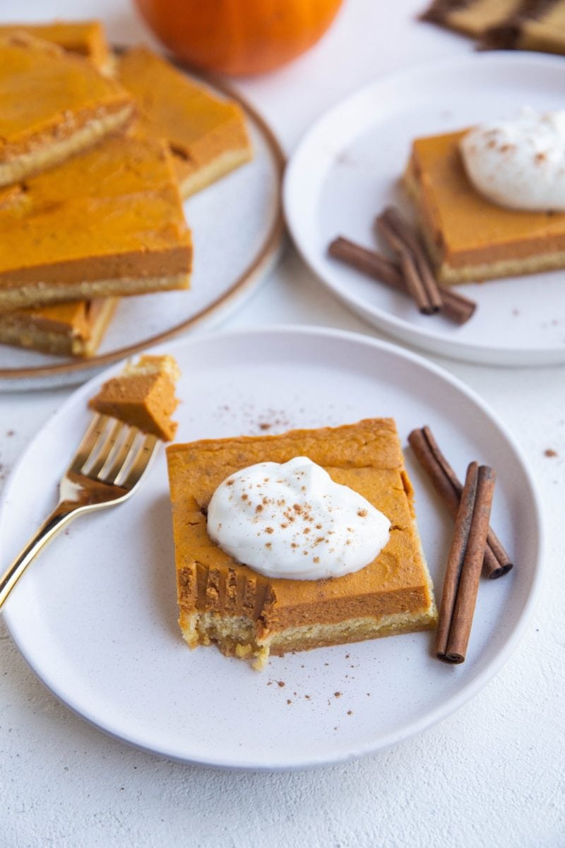 Three plates with slices of keto pumpkin pie on them with one with a bite taken out.