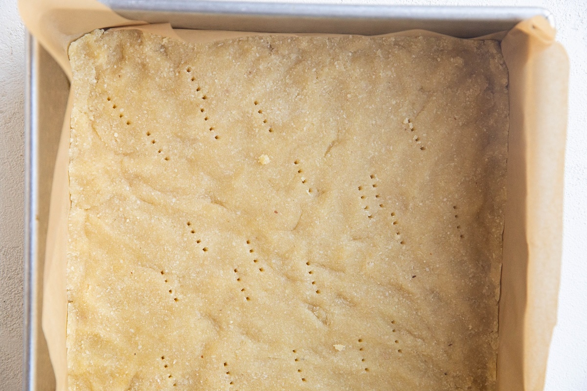 Crust pressed into a cake pan, ready to be baked