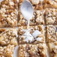 Spoon drizzling glaze over the crumb bars.