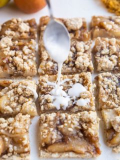 Spoon drizzling glaze over the crumb bars.
