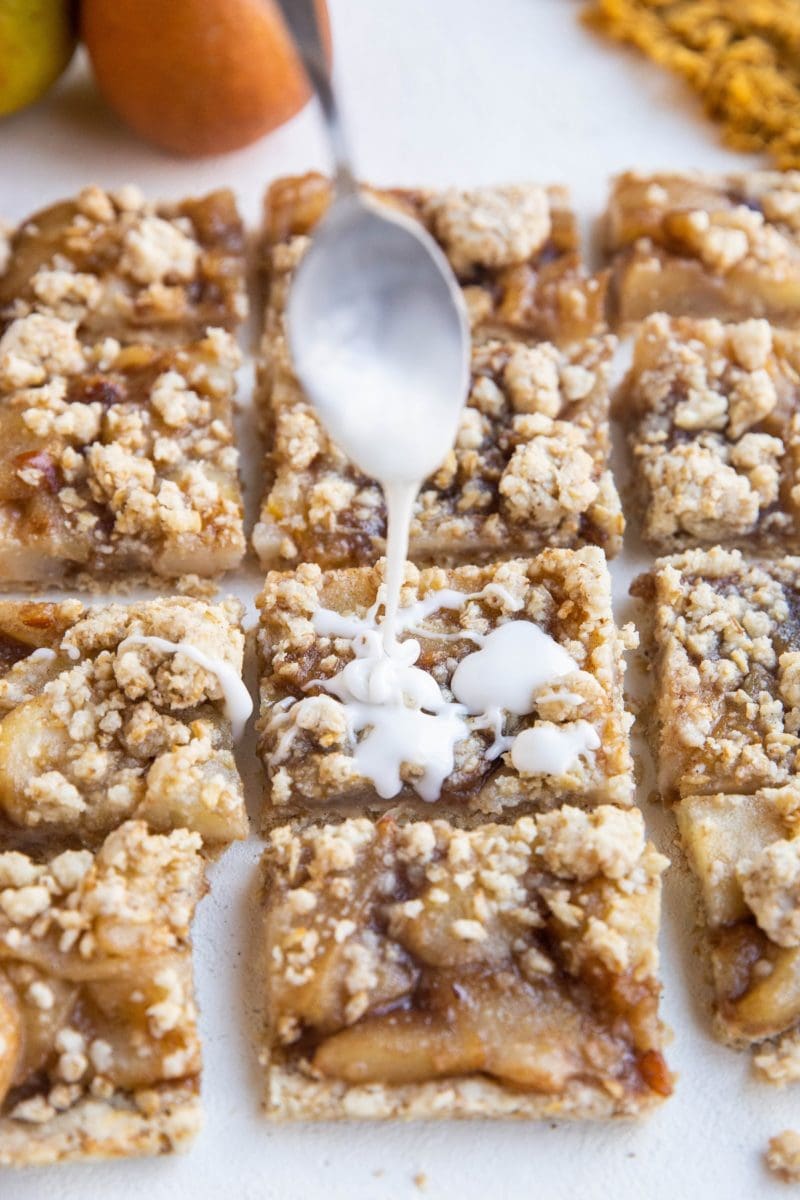 Spoon drizzling glaze over the crumb bars.