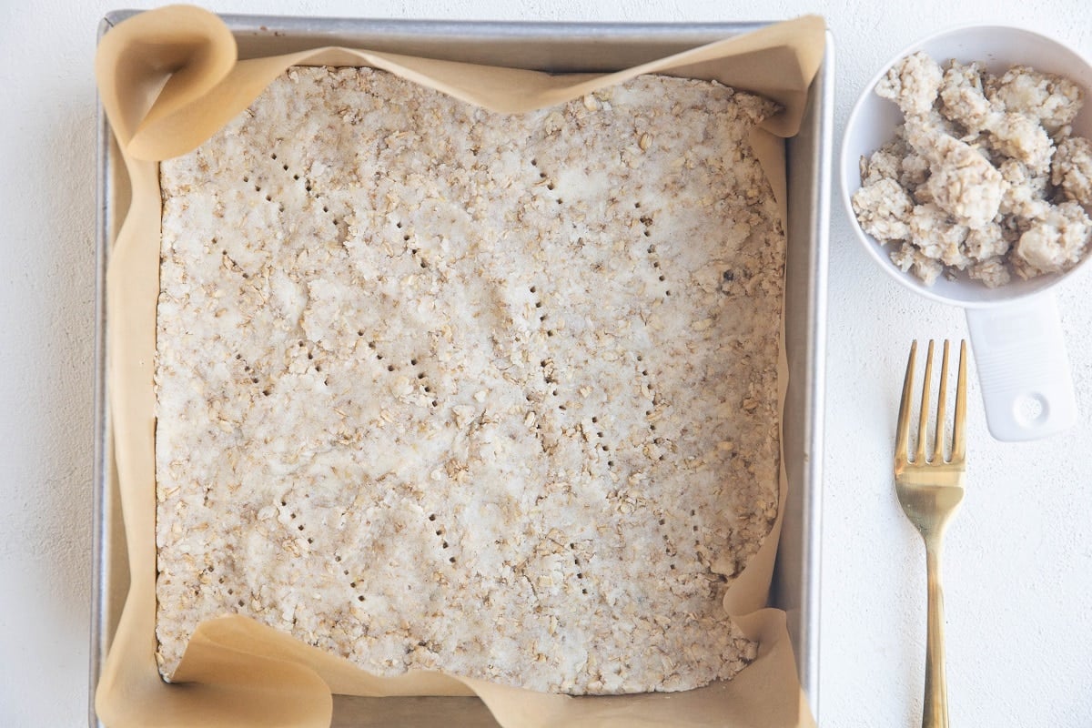 Crust pressed into a baking pan with some reserved crumble topping to the side